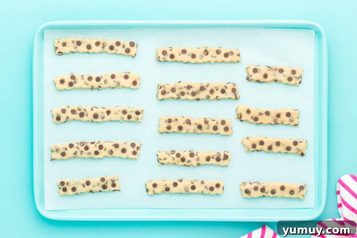 Golden Cookie Fries with Chocolate Chips 16 Unbaked Chocolate Chip Cookie Fries arranged on a parchment-lined baking sheet, ready for chilling.