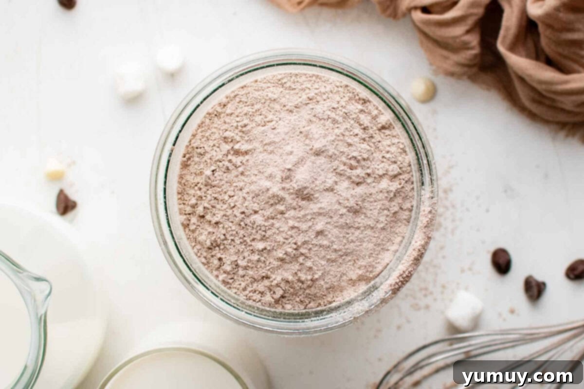 An overhead view of rich homemade hot chocolate mix neatly stored in a clear glass jar, ready for use.