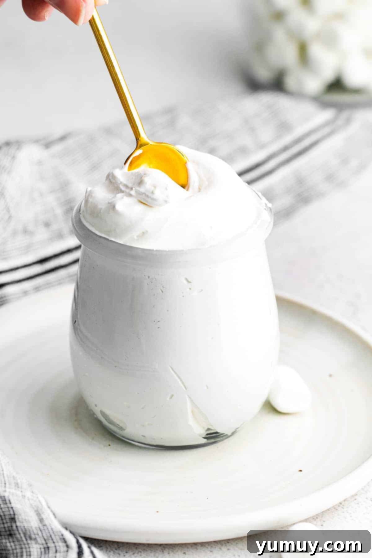 scooping homemade marshmallow fluff from a glass jar with a gold mini spoon.
