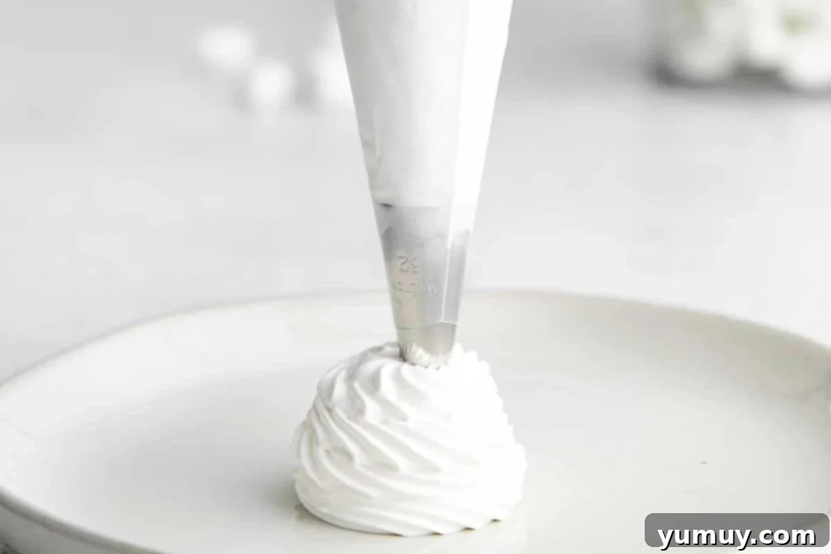 piping homemade marshmallow fluff onto plate with a piping bag.