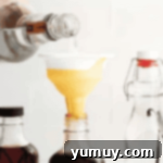 Pouring vodka through a funnel into a bottle of vanilla beans