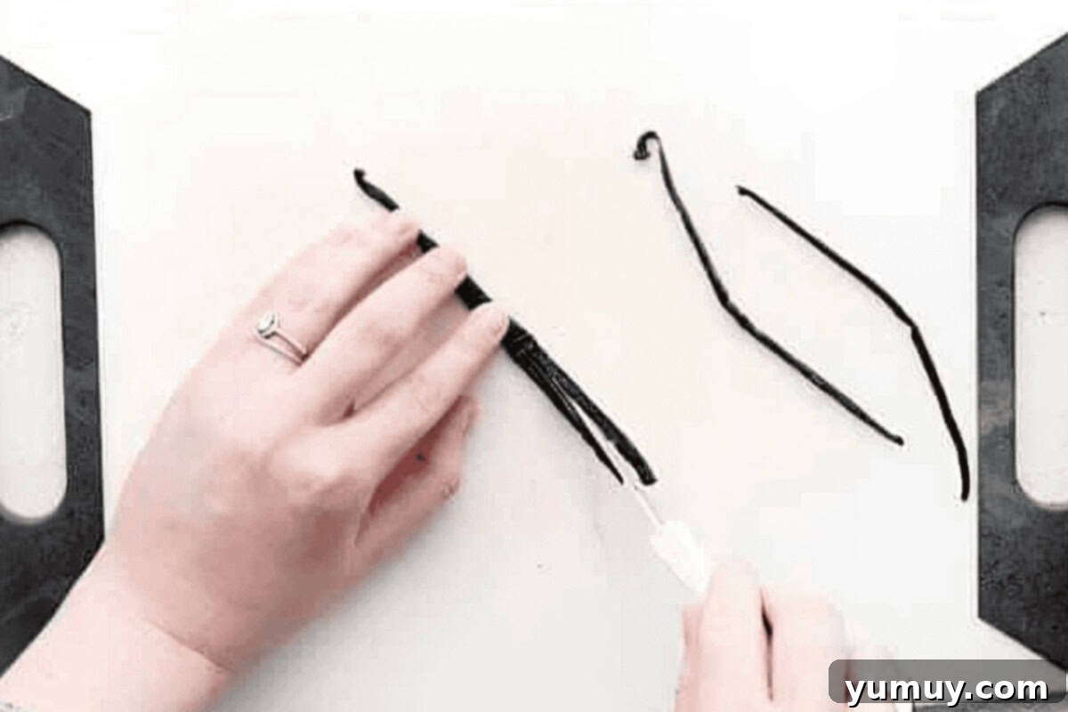 Slicing vanilla beans lengthwise with a paring knife to expose the seeds.