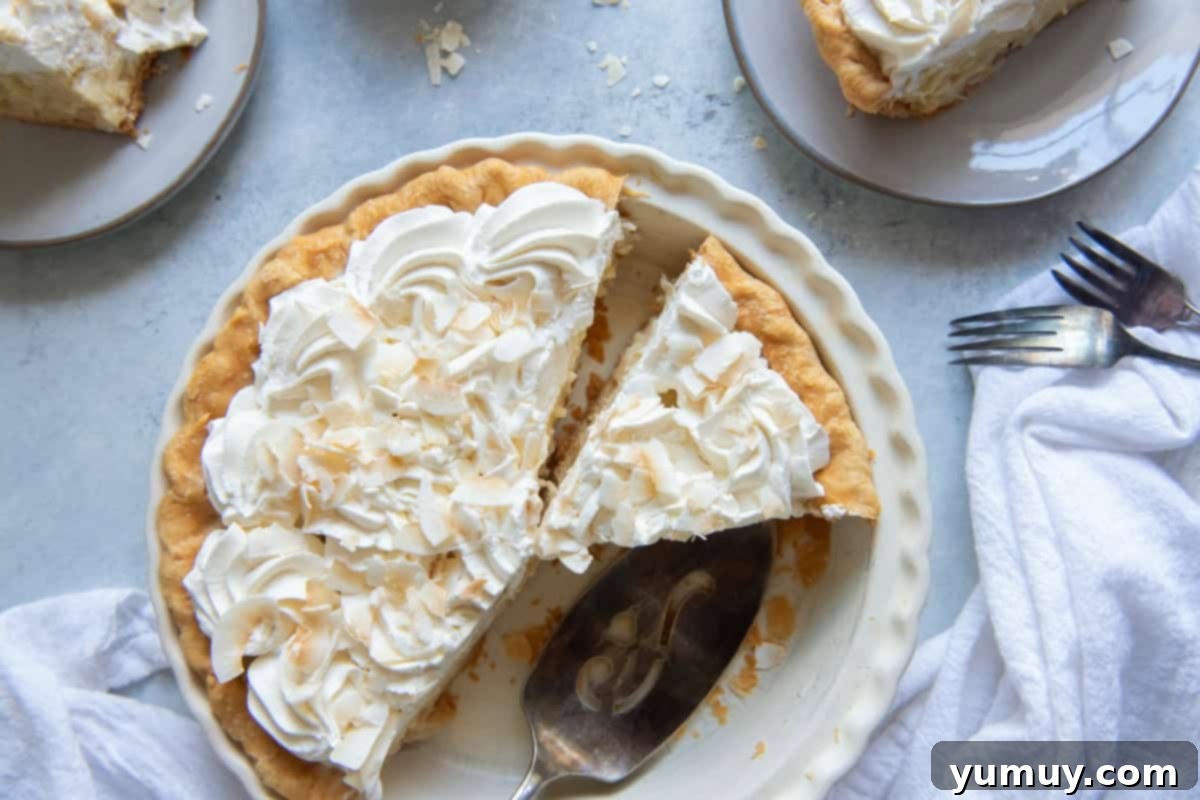Creamy Coconut Bliss 3 overhead view of coconut cream pie with slices missing in a pie pan.