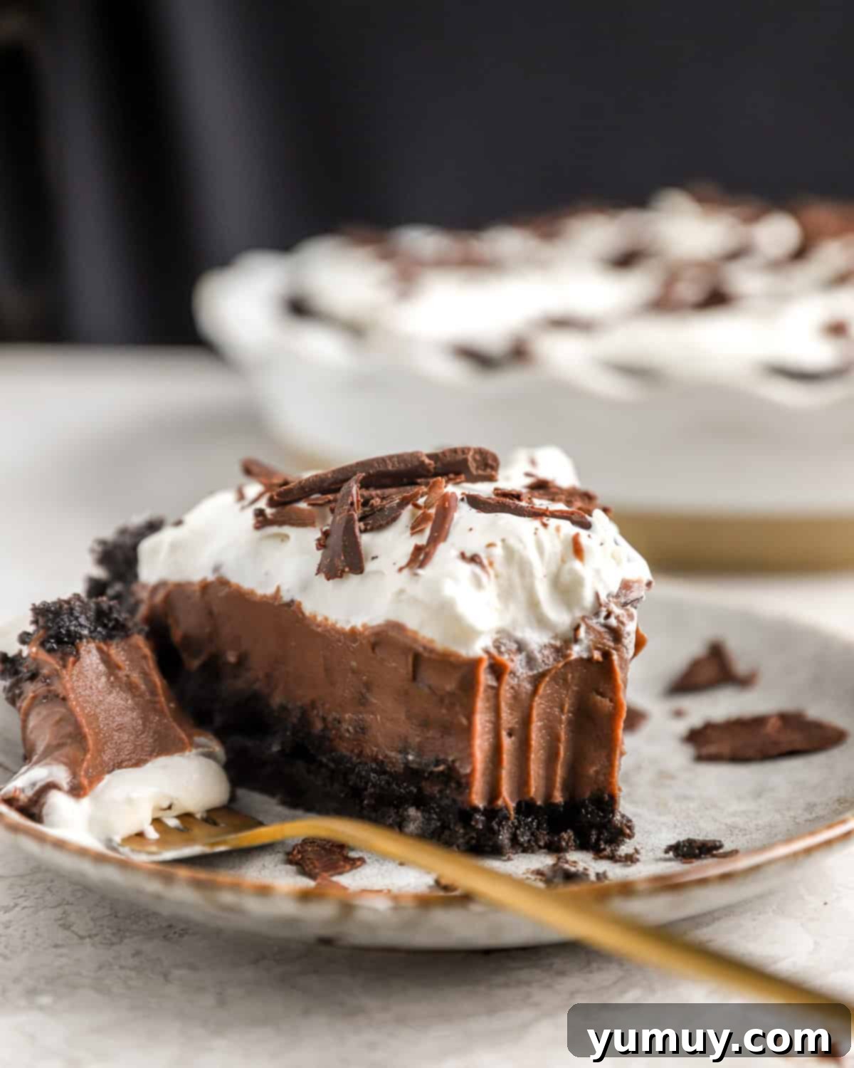 A slice of chocolate cream pie with Oreo crust on a plate.