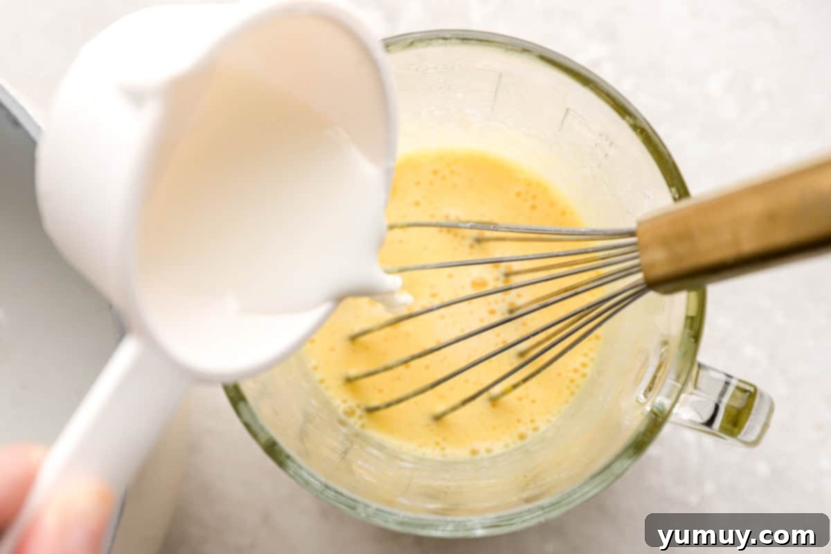 Adding milk to a large glass measuring cup.