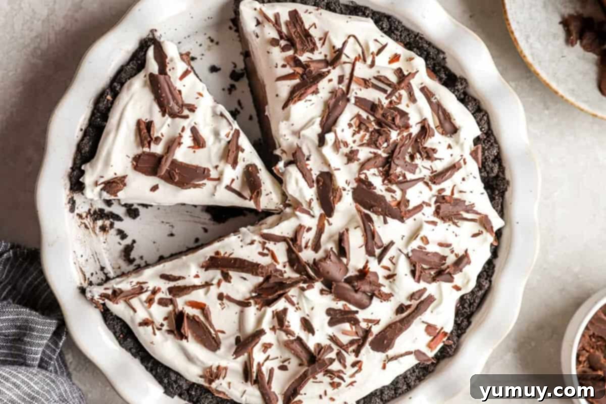 Chocolate cream pie in a white ceramic pie dish, with one slice removed.