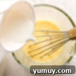 Adding milk to a large glass measuring cup.