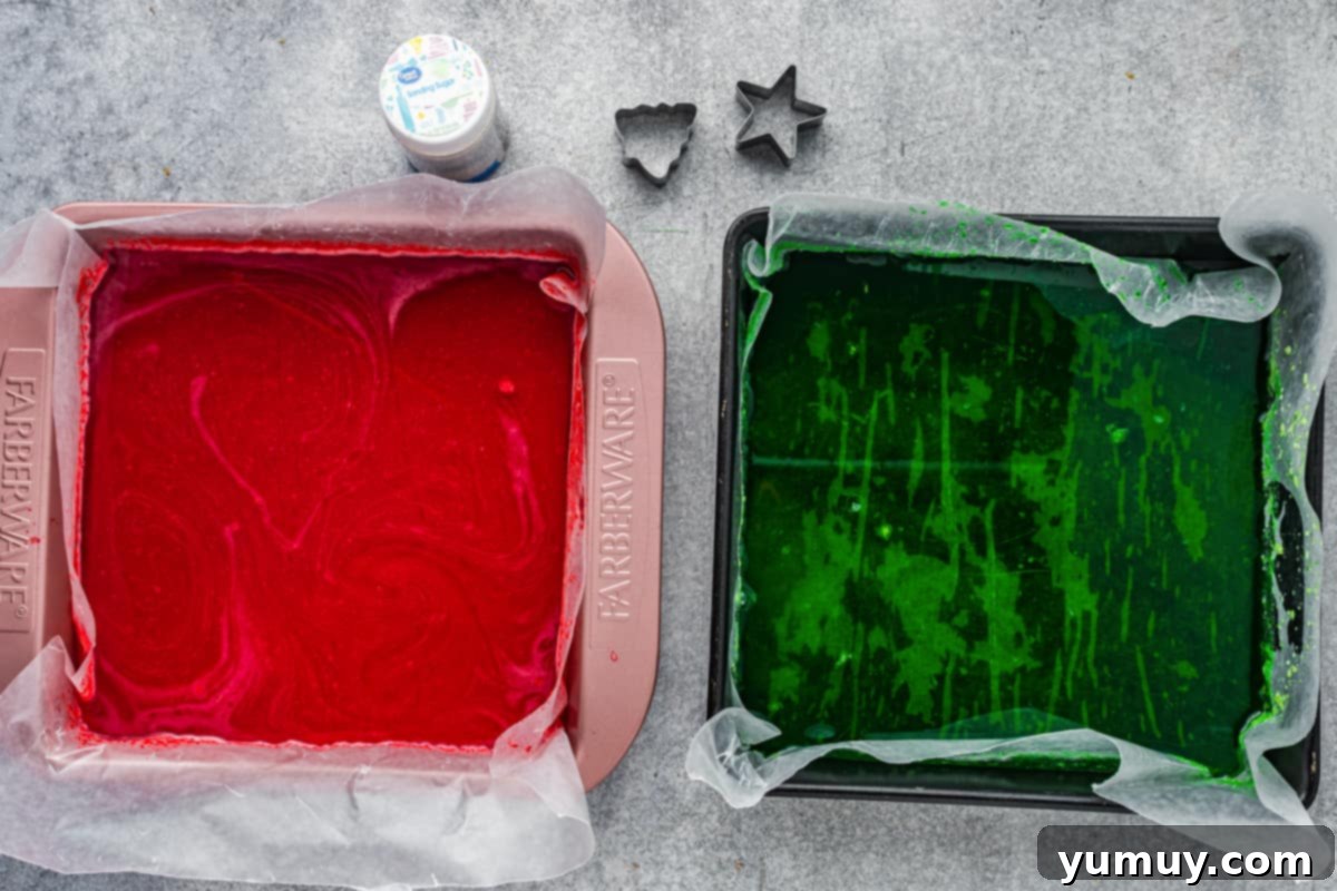 Two baking pans, lined with parchment paper, filled with red and green gelatin sheets, chilling in the refrigerator.