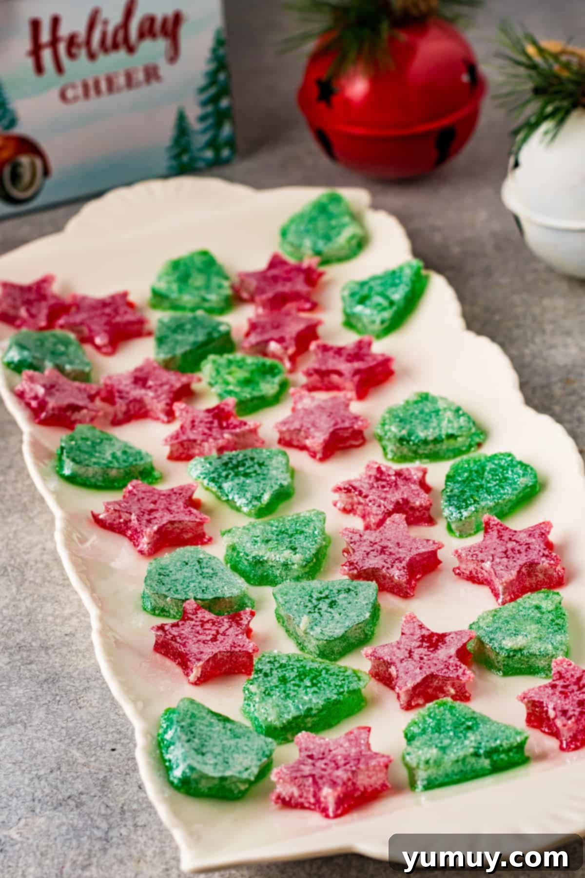 A festive display of red and green Christmas gumdrops, perfectly cut into holiday shapes and coated in sparkling sugar, arranged on a serving tray.