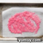 Crafting Custom Colored Sprinkles 6 Newly dyed sprinkles spread out on parchment paper to dry.