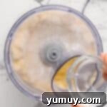 Adding water to ingredients in a food processor.