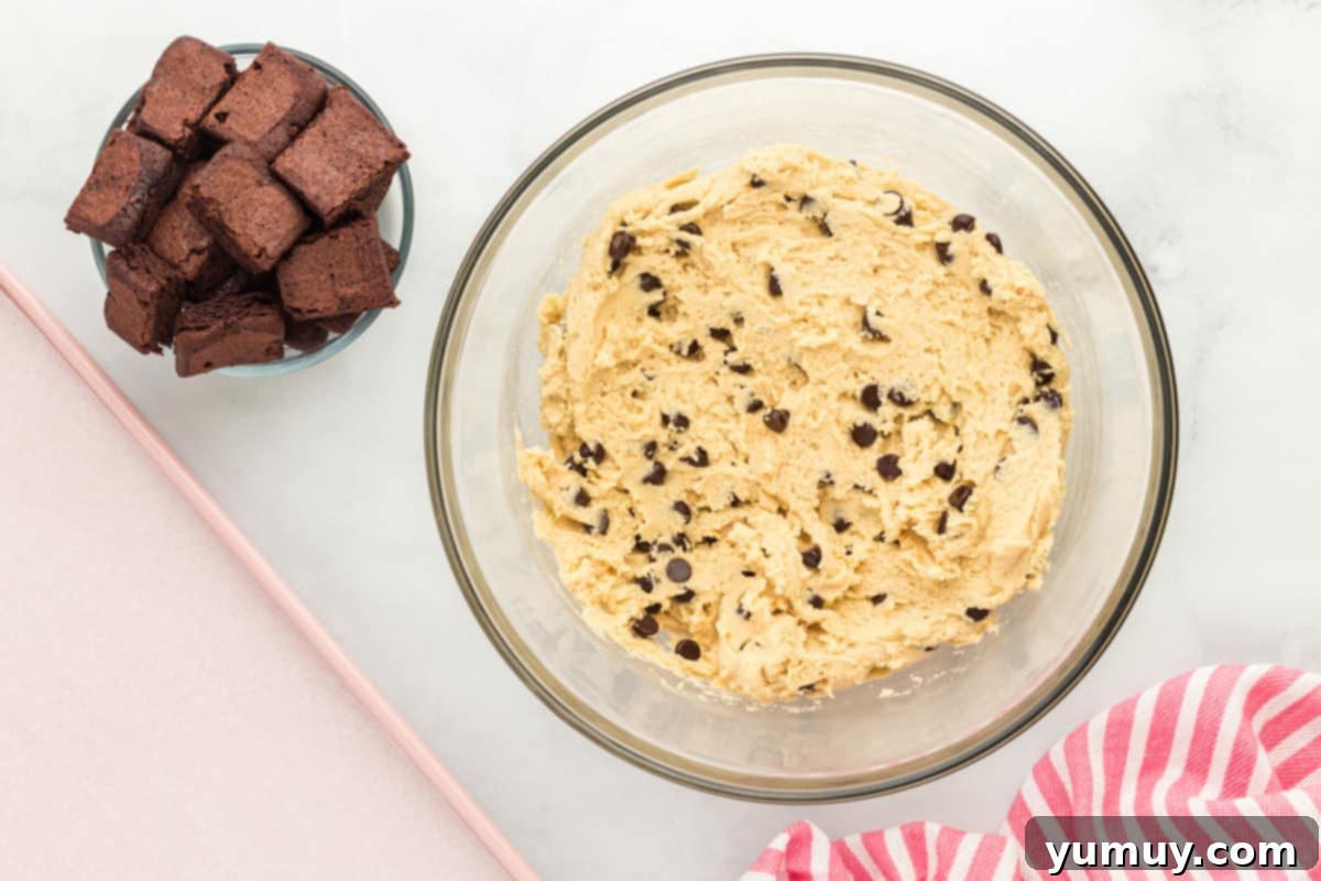 a bowl of chocolate chip cookie dough next to a smaller bowl of brownies cut into cubes