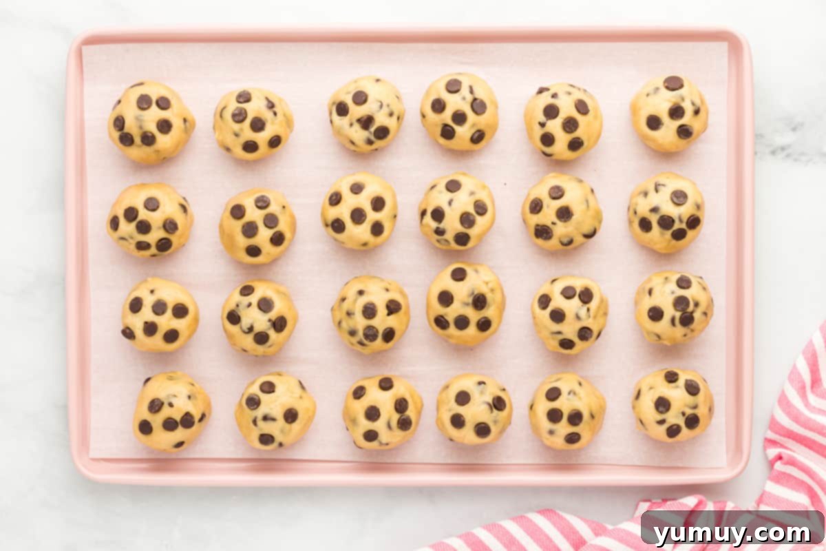 24 brownie stuffed chocolate chip cookies lined on a baking tray