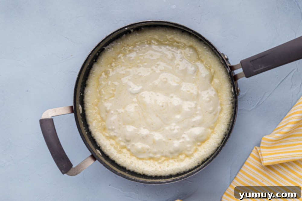 Crispy Marshmallow Squares 6 Melting marshmallows and butter in a pan, creating a smooth, golden mixture.