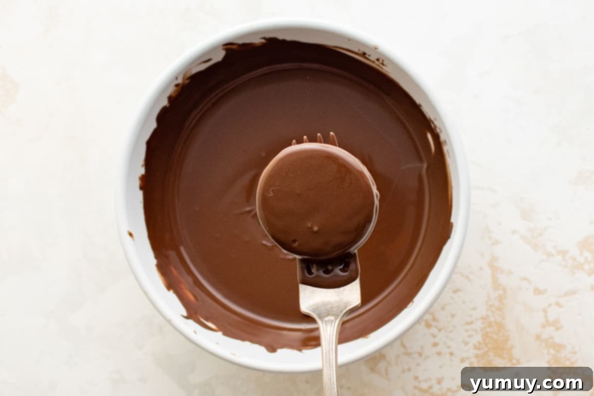 dipping an Oreo into melted chocolate using a fork