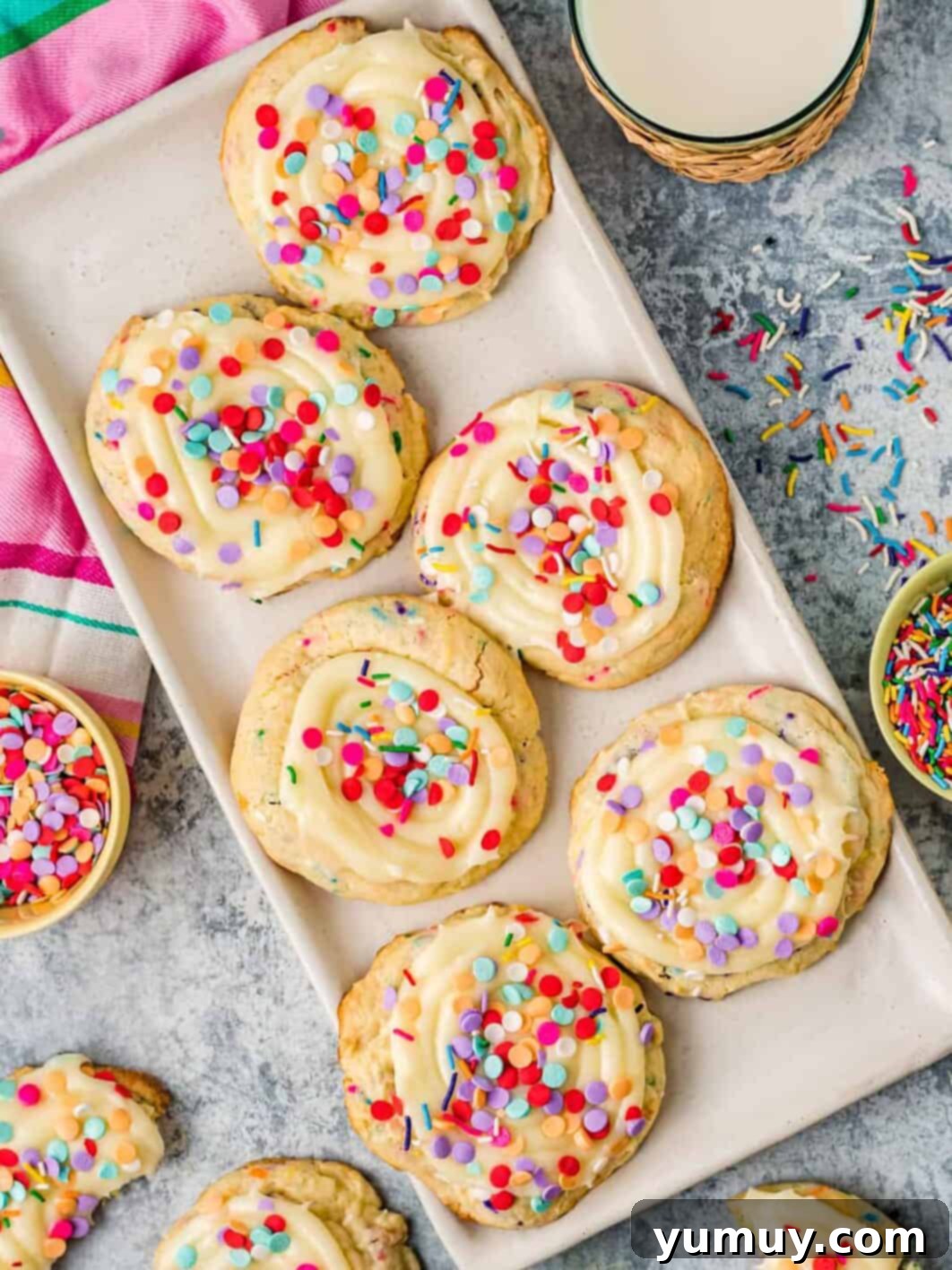 Cake Batter Confetti Cookies 2 A plate of freshly baked confetti cake mix cookies, topped with creamy frosting and rainbow sprinkles, ready to be enjoyed.