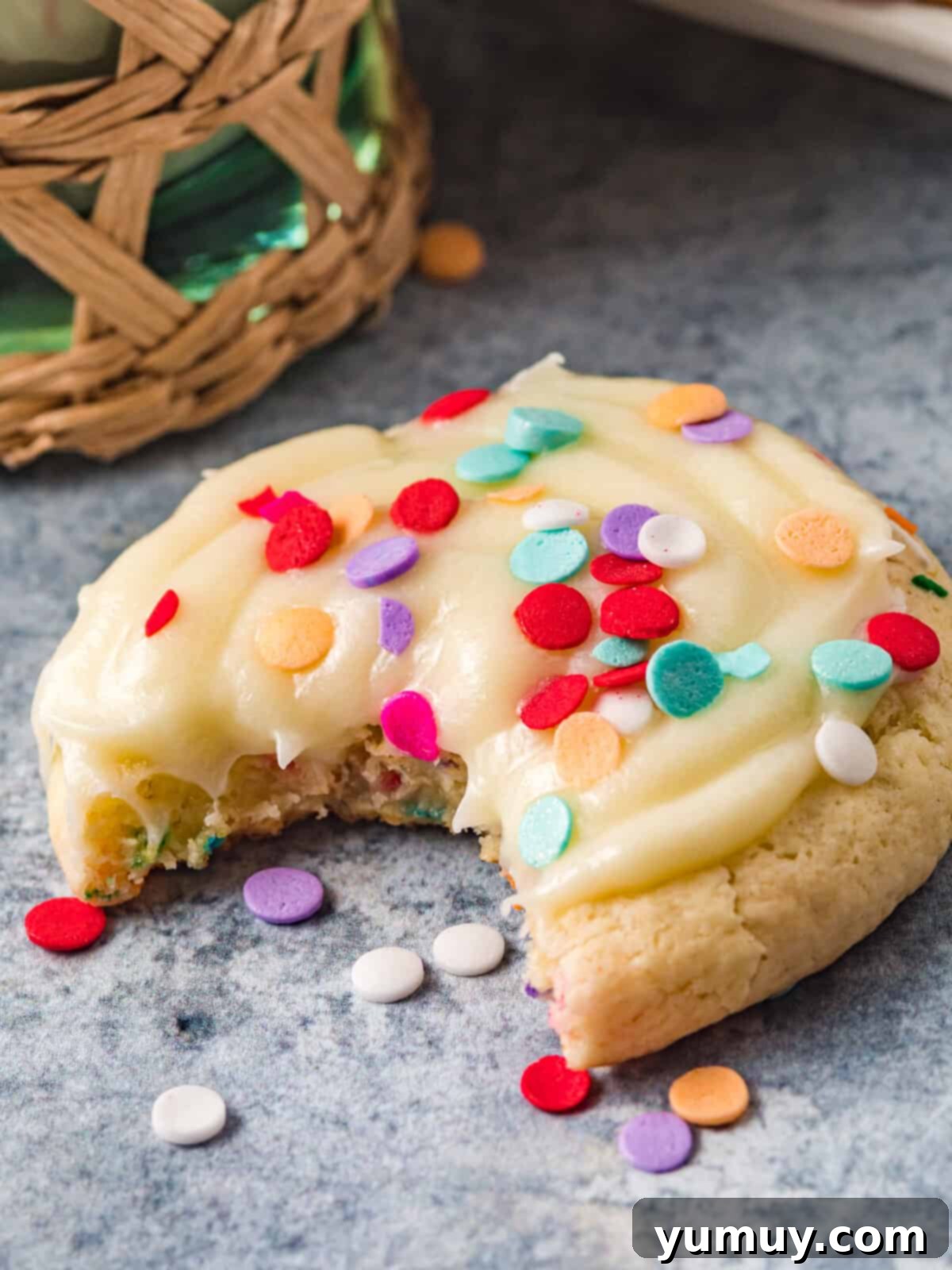 Cake Batter Confetti Cookies 3 A close-up shot of a confetti cake cookie with a perfect bite taken out, revealing its soft, cake-like interior and creamy frosting.