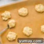 Cake Batter Confetti Cookies 7 Unbaked cookie dough balls with sprinkles arranged on a parchment-lined baking tray, ready for the oven.