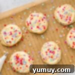 Cake Batter Confetti Cookies 10 Decorated confetti cake mix cookies with creamy frosting and rainbow sprinkles, arranged on a cooling rack.