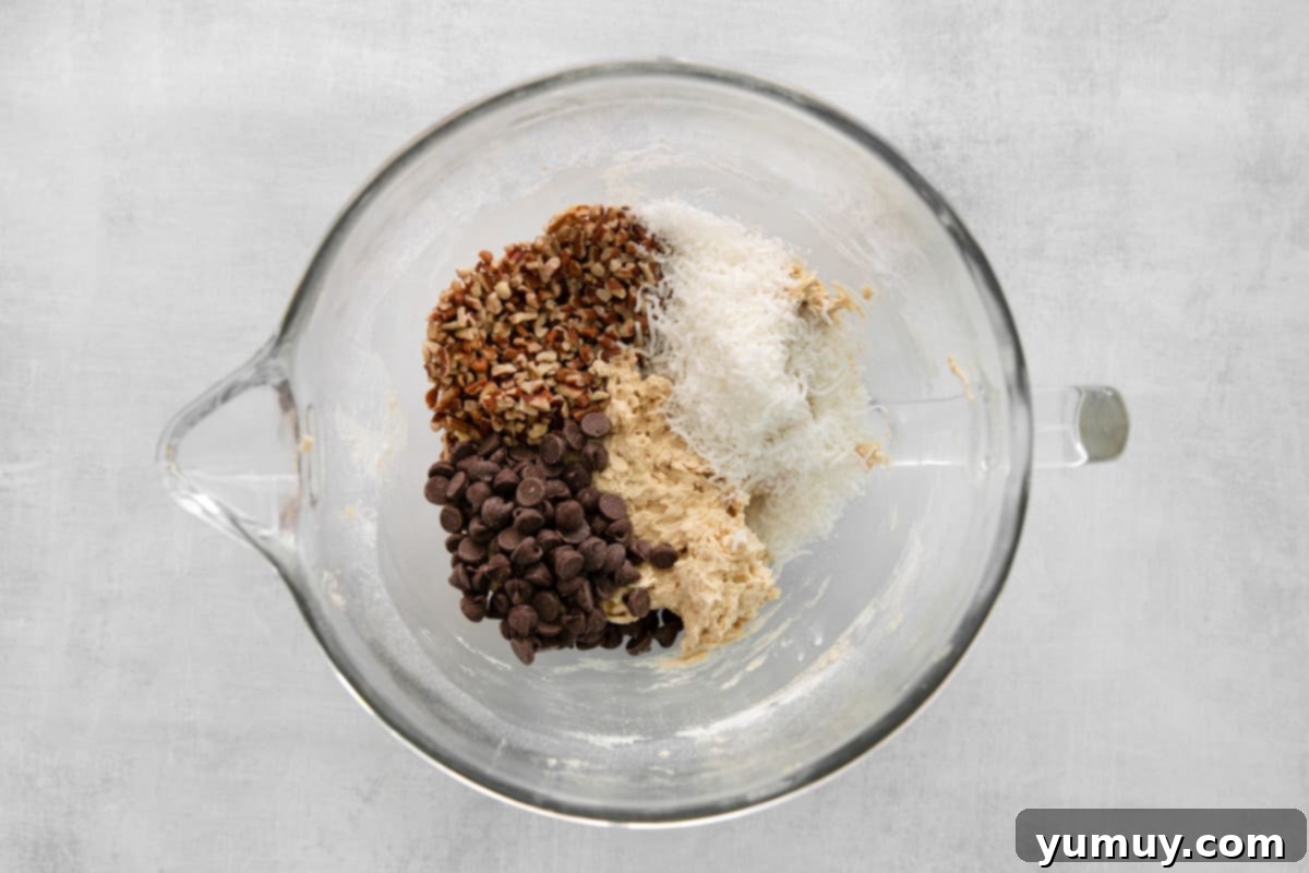 Folding in chocolate chips, coconut, and pecans into the cowboy cookie dough