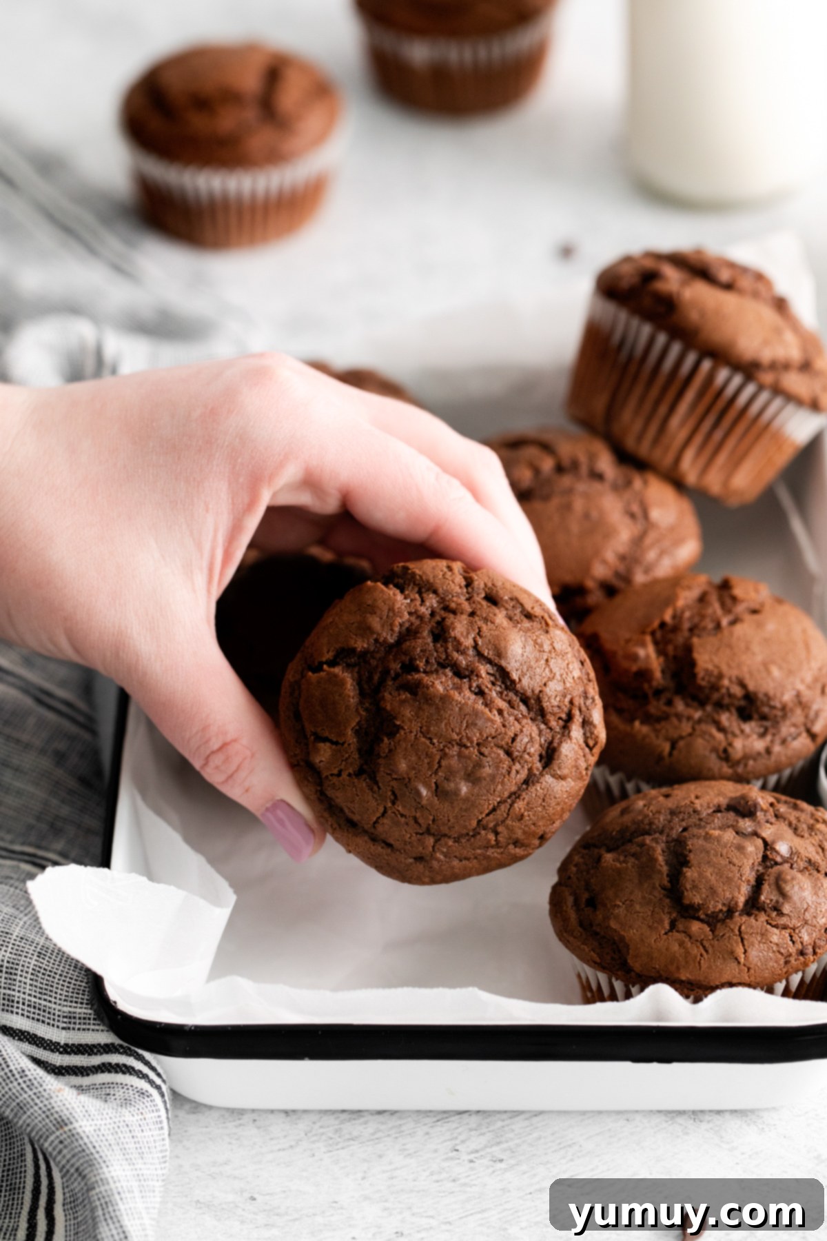 A hand reaching for a warm, freshly baked double chocolate muffin