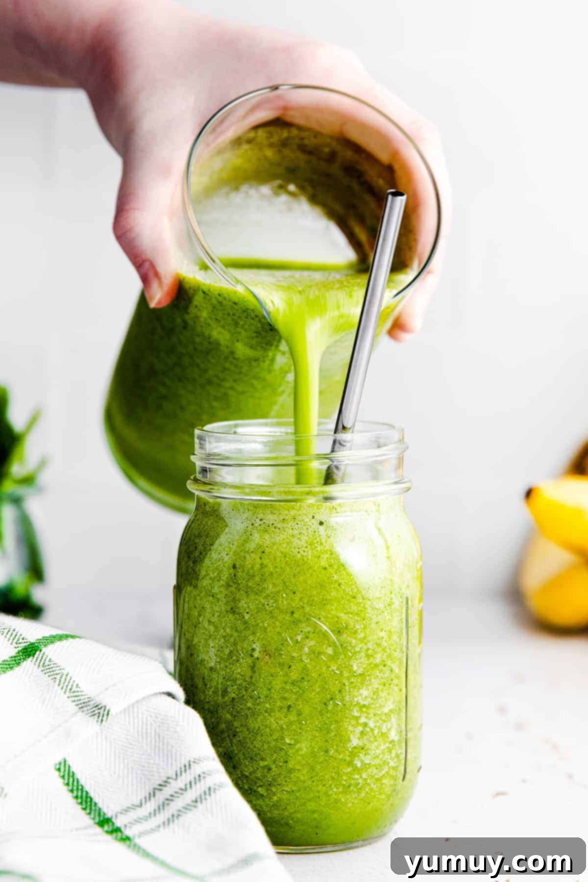 A vibrant green smoothie poured into a glass mason jar, ready to be enjoyed.