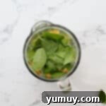Overhead view of ingredients for an island green tropical smoothie in a blender before blending.