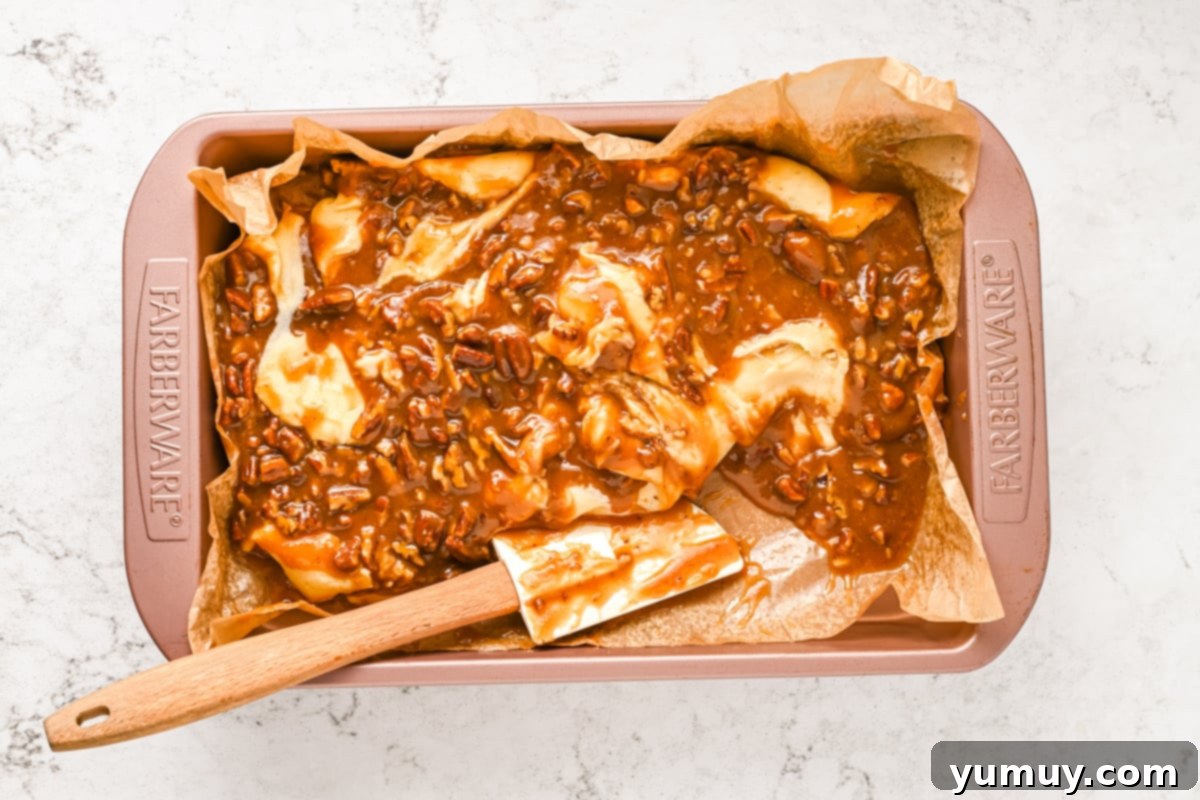 A pan of fudge demonstrating the marbling process, with a spoon gently swirling the praline layer into the white chocolate base.