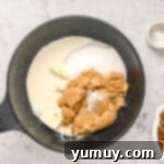 Praline ingredients, including sugars, cream, butter, and baking soda, combined in a large pot.