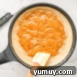 A frying pan with a spoon in it, showing the praline mixture boiling.