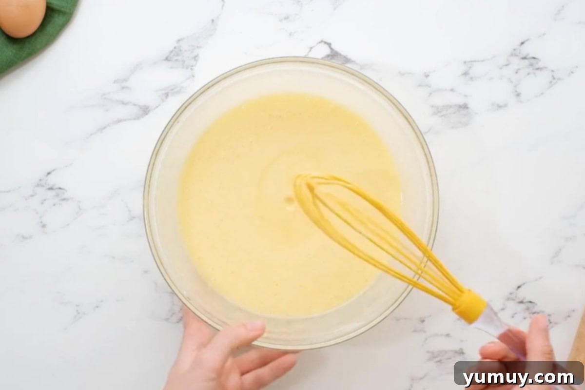 Close-up of the smooth, pale yellow buttermilk pie filling in a glass bowl after all ingredients have been thoroughly whisked together.