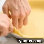Close-up of hands expertly crimping the edges of a pie crust, preparing it for baking.