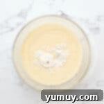 Adding flour, melted butter, buttermilk, lemon juice, vanilla, and salt to the whisked eggs and sugar in a glass bowl.