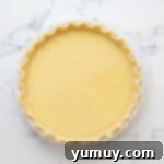 A crimped pie crust in a metal pie pan, filled to the brim with the smooth, uncooked buttermilk pie filling, ready for baking.