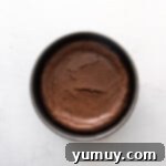 Baked mocha cheesecake cooling in a round springform pan in the oven.