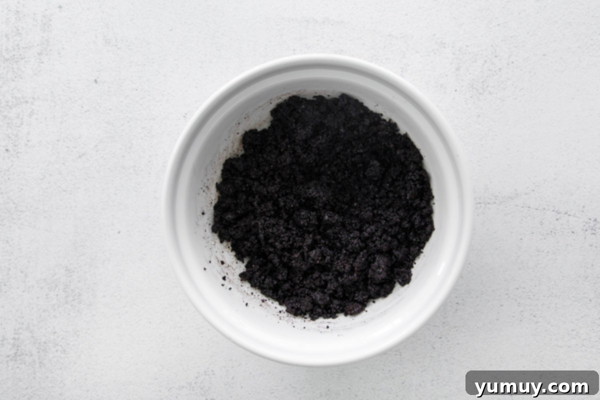 Oreo cookie crumbles and melted butter in a bowl, perfectly mixed for the cheesecake crust.