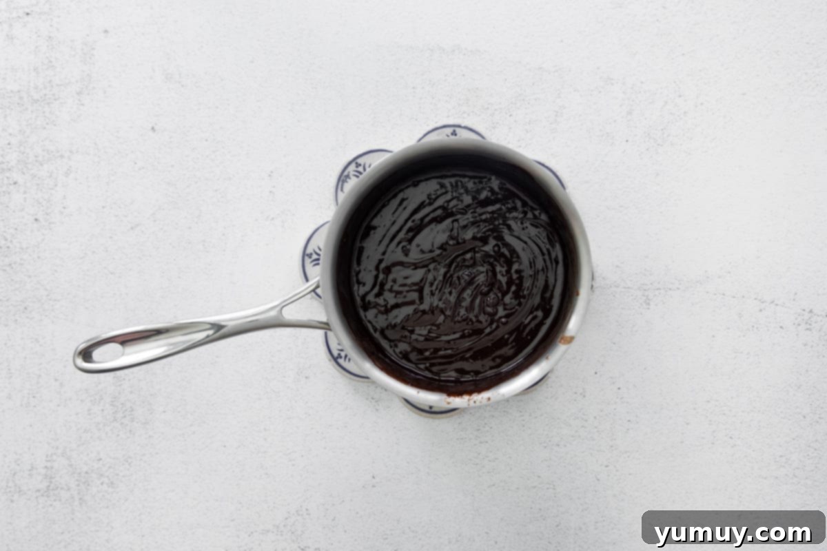 A smooth, glossy mixture of coffee and melted chocolate in a saucepan, infusing with espresso powder.