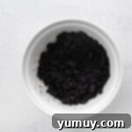 Oreo cookie crumbles and melted butter in a bowl, ready to be mixed for the crust.