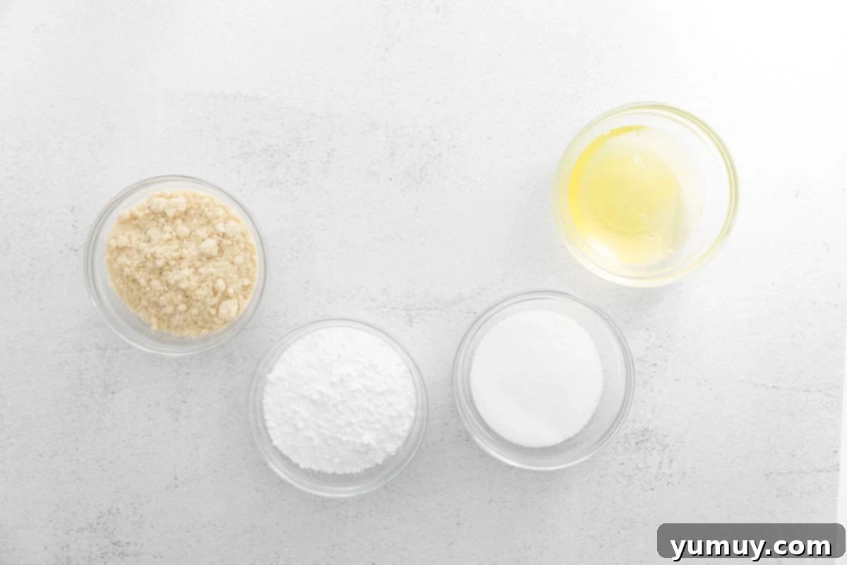 Individual glass bowls filled with precisely measured ingredients for macaron shells, including almond flour, powdered sugar, granulated sugar, and egg whites, arranged neatly on a clean surface, emphasizing preparation.