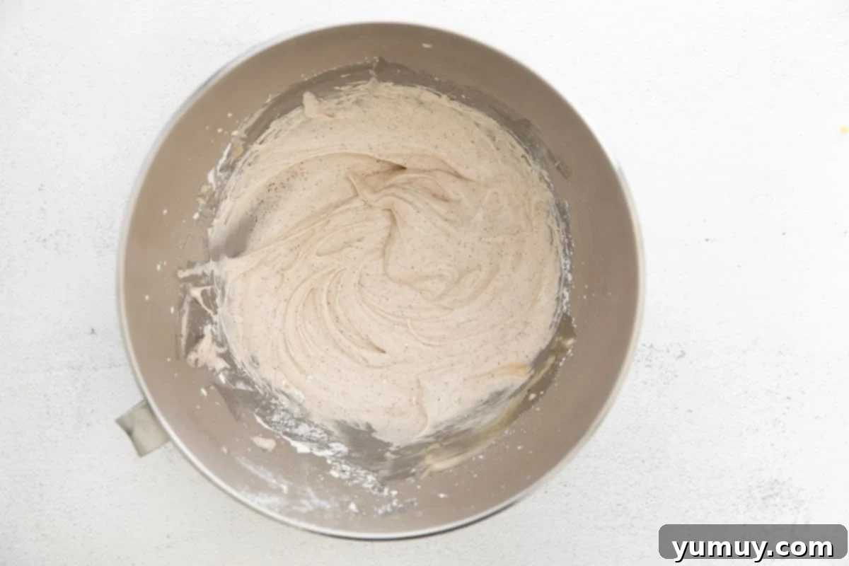 Smooth, whipped tiramisu frosting filling a stainless steel stand mixer bowl, perfectly textured and ready for piping.