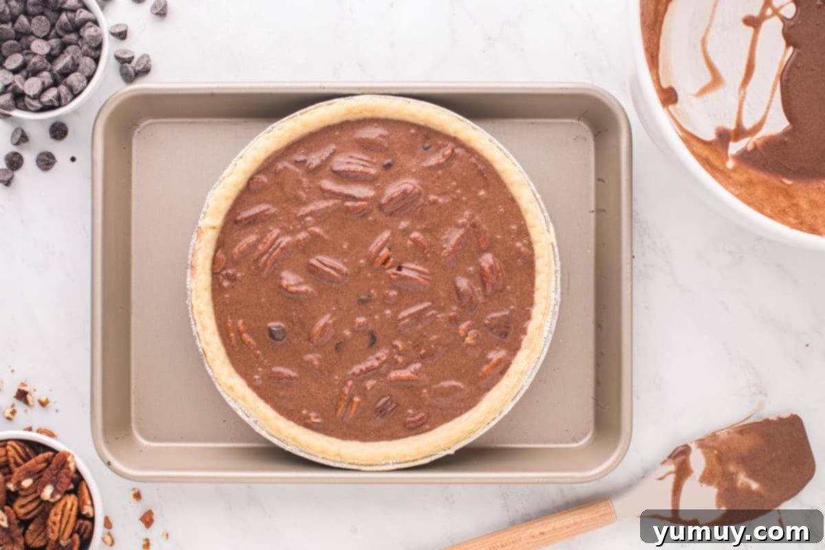 An unbaked chocolate pecan pie, perfectly filled with its rich chocolate and pecan mixture, resting in its golden crust on a baking sheet, ready for the oven.