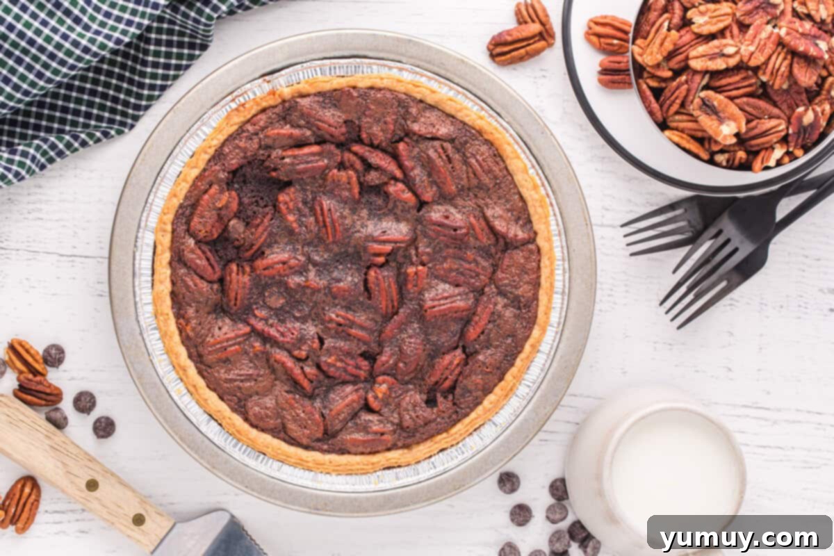An overhead shot of a freshly baked chocolate pecan pie, glistening in its ceramic pie dish, just removed from the oven and ready to cool.