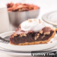 Featured image of a whole chocolate pecan pie, glistening and ready to be sliced.