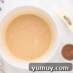 The pecan pie base mixture, now incorporating corn syrup and vanilla extract, in a white mixing bowl.