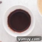 Melted butter and unsweetened cocoa powder being expertly whisked together in a white bowl, transforming into a smooth, dark chocolate butter mixture.
