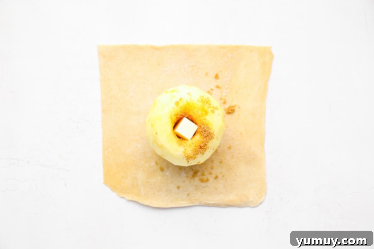Flaky Pie Crust Apple Delights 13 An apple stuffed with cinnamon sugar and butter, perfectly centered on a pie crust square and ready to be folded.