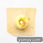 Flaky Pie Crust Apple Delights 7 An apple stuffed with cinnamon sugar and butter on a square of pie crust, ready to be folded.