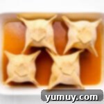 Flaky Pie Crust Apple Delights 10 Apple dumplings arranged in a baking pan with sauce, ready for the oven.