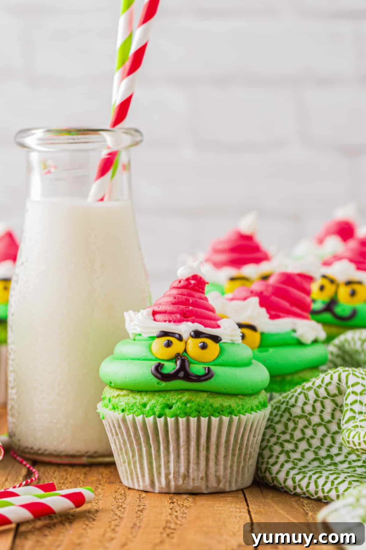 grinch cupcakes on a table with a glass of milk