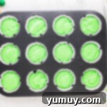 cupcake tin filled with green cupcake batter